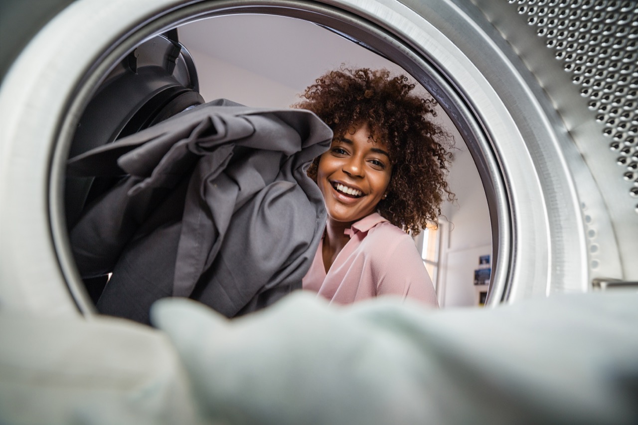 Woman smiling while loading laundry — MW Laundry Valet pickup and delivery service